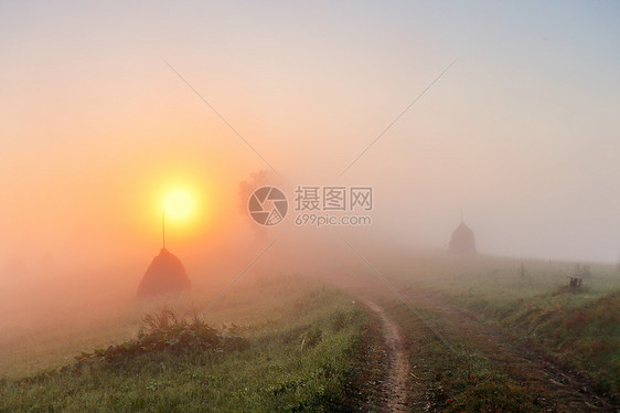 山野上的日出朦胧的乡村山丘上的干草堆道路雾蒙蒙的秋天早晨山上图片