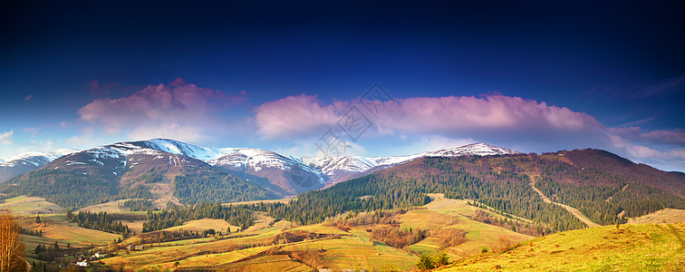 春季雪山全景晨光中的山脉深蓝色的天空田园诗般的春天,高山晨景,背景中新鲜的绿色草地白雪皑皑的山顶图片