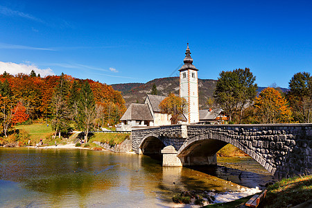 五彩缤纷的秋日古老的村庄与旧桥教堂教堂塔石桥博欣杰湖高山村里比奇夫拉兹,斯洛文尼亚图片