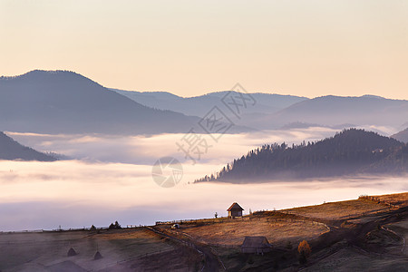 秋天雾蒙蒙的早晨,山口上的小茅屋山村山里的旧农场背景雾天空的云背景