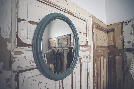 圆镜挂磨碎的木墙上,衣柜里剥落的白色油漆图片
