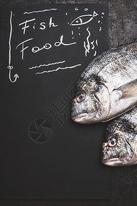 鱼食,黑色黑板背景上的手写文字与生鱼,顶部视图,图片