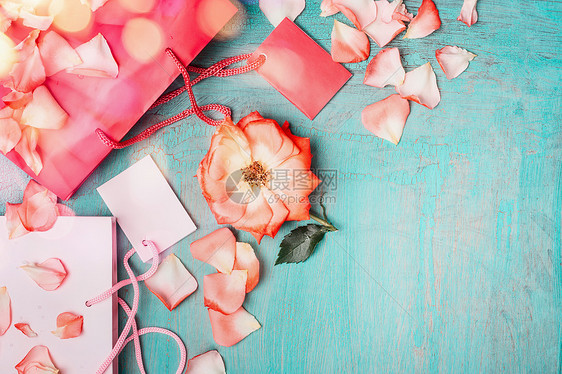 粉红纸购物袋与玫瑰空白标签蓝色绿松石背景,顶部视图,边界图片