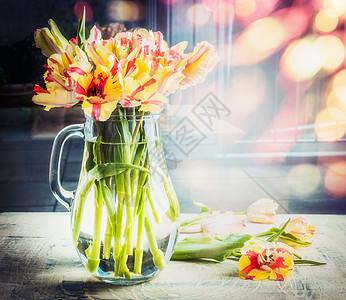 明亮的郁金香花璃水壶阳光明媚的春天背景下的桌子上,与bokeh,正视图图片