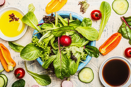 顶部的绿色健康沙拉碗与敷料配料,饮食,素食纯素食品的图片