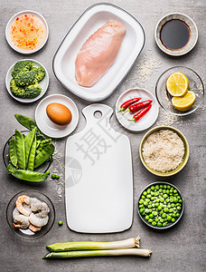 炒米烹饪配料与鸡肉,鸡蛋,虾绿色蔬菜周围的白色切割板灰色的石头背景,顶部视图,边界亚洲菜图片