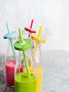 各种五颜六色的冰沙瓶与饮用吸管绿色,黄色,红色,正视图,特写图片