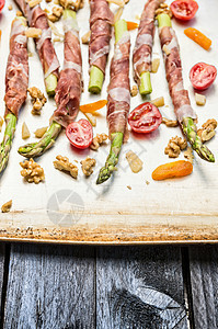 绿色芦笋裹帕尔马火腿与西红柿,帕尔马干酪,核桃干杏,准备烹饪,图片