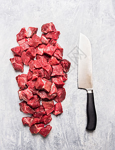 生牛肉勾腿肉丁炖肉刀浅灰色木制背景,顶部视图背景图片