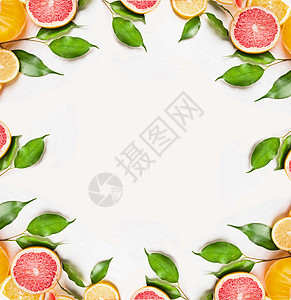 柑橘片的橙色,柠檬柚子与绿叶白色的木制背景,框架,顶部视图图片