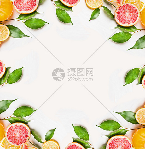 柑橘片的橙色,柠檬柚子与绿叶白色的木制背景,框架,顶部视图图片
