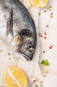 生多拉多鱼与柠檬香料纸上白色的木制背景,顶部视图图片