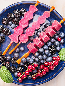 粉红色冰棒冰淇淋与新鲜的夏季浆果红色醋栗,黑莓,蓝莓白色木制背景,图片
