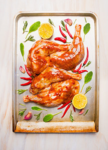 生鸡腿与红辣酱,鼠尾草柠檬烘焙托盘白色木制背景,顶部的图片