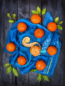 蓝色毛巾上绿叶的橘子,深色木制背景,顶部景色图片