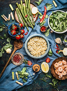 煮熟的藜麦与绿色芦笋其他蔬菜成分,健康烹饪黑暗的乡村厨房桌子背景与烹饪勺子碗,顶部视图清洁机食品的背景图片