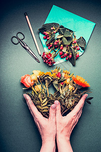 女手着个创造的秋季花花店工作的桌子背景与打开的信封,剪刀,铅笔,顶部的视图邀请,问候假期,图片