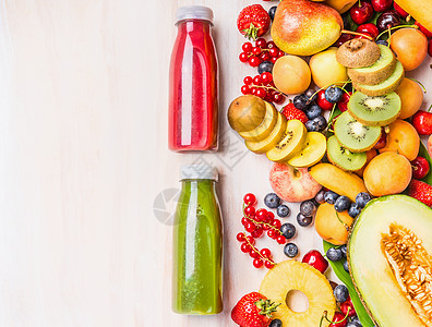 红色绿色冰沙果汁饮料瓶与各种新鲜的机水果浆果成分白色木制背景,顶部视图健康食品素食观念图片