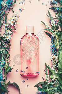 天然化妆品瓶粉红色苍白背景与植物花卉,顶部视图,花卉化妆品,植物香味图片