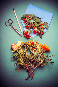 秋季花卉安排桌子上的工作与剪刀,信封丝带,顶部视图图片