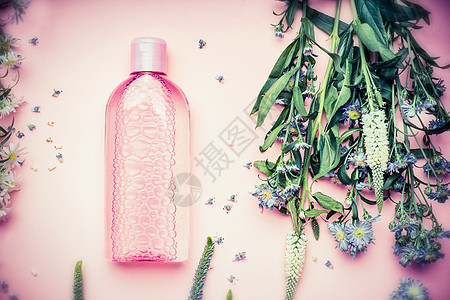 塑料瓶与滋补胶清洁水与新鲜草药花卉粉红色的背景,顶部视图美容,皮肤,头发身体护理图片