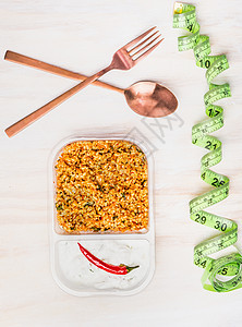 健康饮食午餐与蒸粗麦粉沙拉酸奶素食沙拉饭盒塑料包装与餐具测量磁带木制背景,顶部视图图片