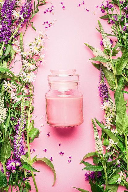天然草药护肤美容璃罐与奶油乳液新鲜草药花卉粉红色背景,顶部视图,垂直美容,皮肤头发护理的图片