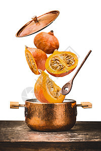 铜锅与飞南瓜与刀,打开盖子木勺桌子上,隔离白色背景,正视图秋季季节食谱饮食背景图片