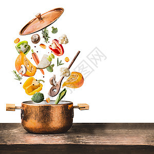 健康的素食饮食烹饪与各种飞斩蔬菜成分,烹饪锅勺子木制桌子上,隔离白色背景,正视图清洁食品的图片