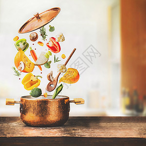 健康的素食饮食烹饪与各种飞行切碎的蔬菜成分,烹饪锅勺子桌子厨房背景,正视图清洁食品的图片