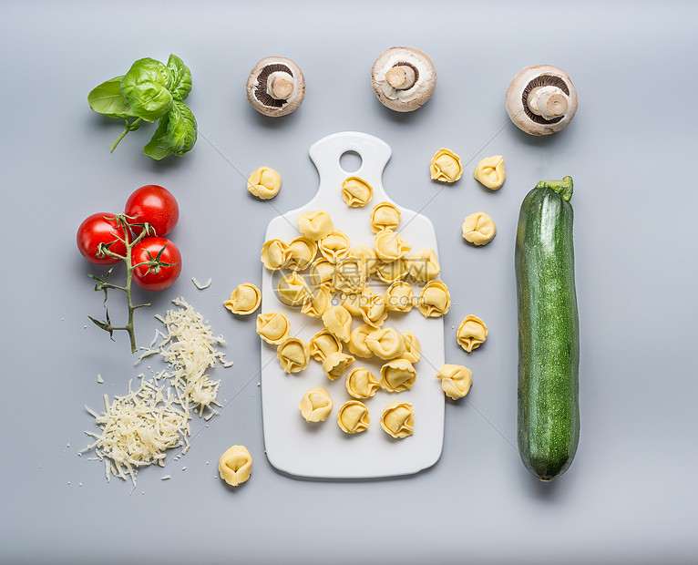 托特里尼与西葫芦,蘑菇素食烹饪原料厨房桌子背景与切割板,顶部视图,平躺健康的烹饪饮食意大利食品图片