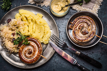 正宗的食物与烤肠土豆泥酸甘蓝沙拉,盘子与餐具,顶部视图,德国食品图片