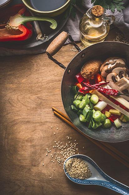 炒锅与素食亚洲美食成分,炒与切碎的蔬菜,香料,芝麻筷子乡村木制背景,顶部的景观中国泰国食品烹饪图片