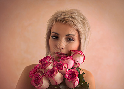 轻漂亮的女人着粉红色的玫瑰她很满意情人节国际妇女节庆祝活动图片
