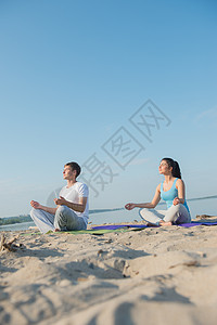 轻夫妇早上海滩上瑜伽冥想图片