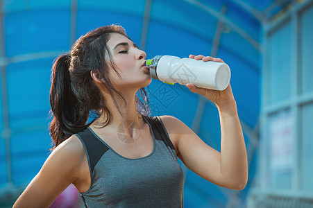 健身美丽的女人喝水出汗后,夏季炎热的日子城市锻炼女运动员锻炼后图片