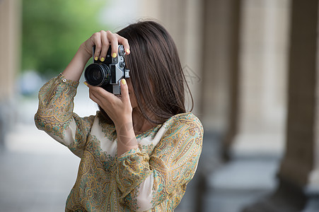 快乐的旅行者女孩城市街道上用复古相机拍摄历史建筑的照片图片