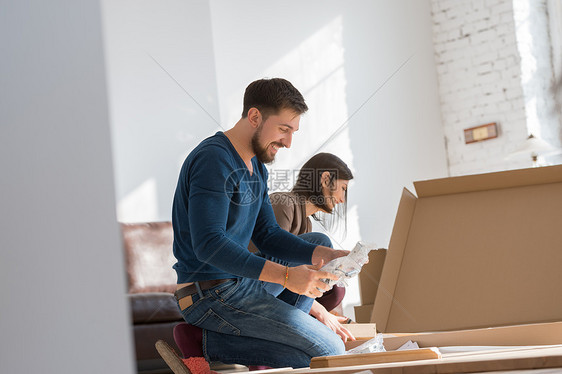 幸福的轻夫妇把自己装的家具合,因为他们搬进了他们的新房子图片