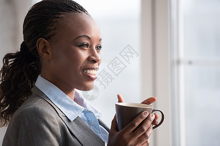 个女商人办公室工作时喝咖啡的坦率形象选择聚焦图片