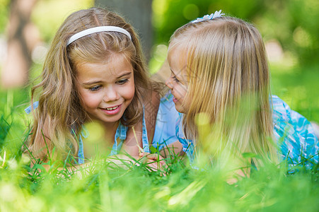 两个小妹妹夏天的公园里玩得很开心,边躺草坪上图片