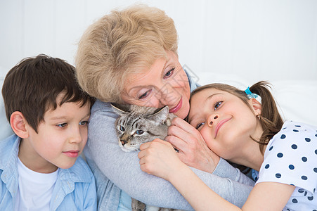 孩子与猫素材微笑的祖母孙子与奶奶的猫拥抱沙发上的肖像背景