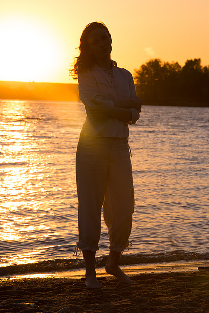 轻的女人夕阳下海滩上散步全长肖像