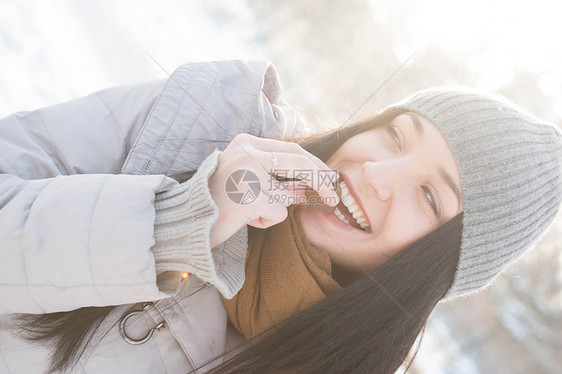 穿着冬装的轻女人吃着阳光照亮的饼干图片