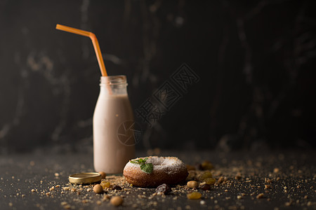 糖粉甜甜圈与薄荷叶奶瓶暗石背景图片