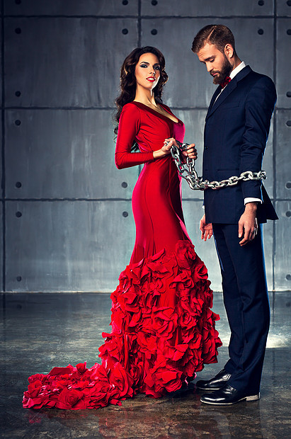 轻的快乐的女人穿着红色的衣服,抱着男人沉重的链子上优雅的晚装图片
