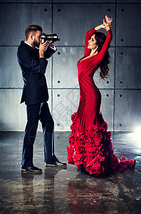 穿着红色连衣裙的轻女人向男人摄影师摆姿势优雅的晚装图片