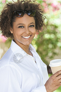 美丽的轻混血黑人非裔美国妇女微笑着戴着太阳镜,喝着外卖的咖啡外图片