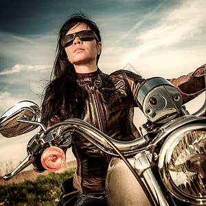 骑着摩托车穿着皮夹克的自行车女孩看着夕阳图片