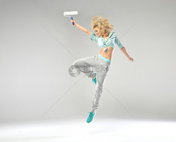 漂亮的女人用油漆滚筒跳跃图片