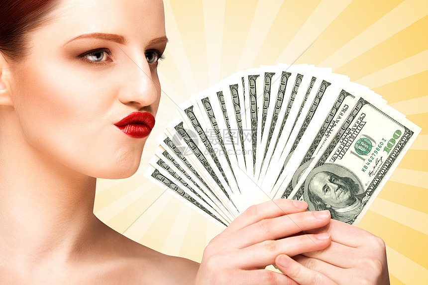 个女孩的创意肖像美丽的脸身体握着手扇由100美元的货币钞票彩色抽象